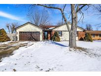 Charming single-story home with a brick and siding exterior, a brown garage door, and a snow-covered front yard at 4925 Royal Orbit Ct, Indianapolis, IN 46237