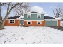 Charming two-story home with a brick facade, teal accents, and a spacious front yard covered in snow at 704 Airport Rd, Brownsburg, IN 46112