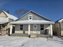 Charming home featuring a covered porch, and snow-covered yard, offering a cozy curb appeal at 724 E Beecher St, Indianapolis, IN 46203