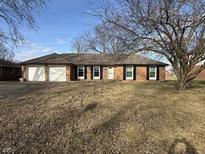 Charming brick ranch-style home with a well-maintained lawn, a two-car garage, and beautiful dark shutters at 806 Country Ln, Anderson, IN 46013