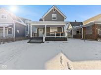 Charming home with a covered front porch and snow-covered front yard at 234 N State Ave, Indianapolis, IN 46201
