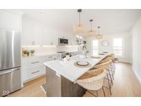 Open kitchen showcases a large island with seating, white cabinetry, quartz counters, and stylish pendant lighting at 4981 E County Road 200 S, Avon, IN 46123