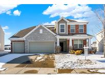 Charming two-story home featuring a brick and stone facade, attached garage, and snow-covered front yard at 5648 Juniper Ct, Whitestown, IN 46075