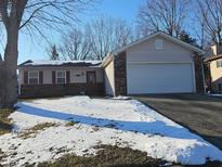 Charming one-story home with attached garage and a brick and vinyl facade, with snow covered lawn at 5816 Coppock Ln, Indianapolis, IN 46221