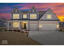 Beautiful two-story home with brick facade and attached three-car garage at sunset at 6723 Collisi Pl, Brownsburg, IN 46112