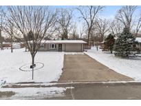 Charming ranch-style home featuring a spacious driveway and well-maintained front yard covered in a blanket of fresh snow at 6907 Buick Dr, Indianapolis, IN 46214