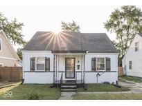 Charming home featuring white painted brick, a covered porch, and mature trees creating an inviting curb appeal at 1467 N Euclid Ave, Indianapolis, IN 46201