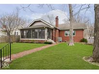 Charming brick home featuring a lush lawn and a cozy sunroom, perfect for relaxing or entertaining guests at 6185 N Delaware St, Indianapolis, IN 46220