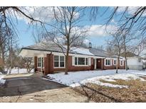 Charming brick home with a carport, well-manicured lawn, and a mix of mature trees at 6711 E 10Th St, Indianapolis, IN 46219