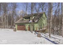 Side view of the two-story home featuring an attached garage and a quaint wooded lot at 1032 E Woodall Ct, Martinsville, IN 46151