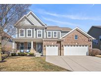 Charming two-story home with a brick and gray exterior, well-manicured lawn, and a spacious three-car garage at 15296 Ellington Dr, Fortville, IN 46040