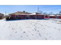 Charming single story home with attached garage and snow covered lawn at 2021 E 9Th St, Anderson, IN 46012