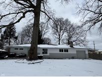 Charming single-story home with a gray and white exterior and snow-covered yard at 7406 E 33Rd St, Indianapolis, IN 46226