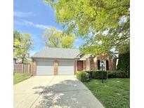 Charming red brick home with a well-maintained lawn, mature trees, and an attached two-car garage at 9788 Pine Ridge North Dr, Fishers, IN 46038