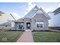 Charming brick home featuring a covered porch with seating, landscaping, and a welcoming brick pathway to the front door at 1225 Stonehaven Dr, Westfield, IN 46074