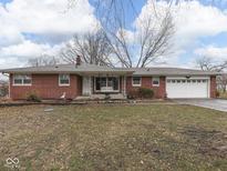 Charming brick home with a well-maintained lawn, attached garage, and cozy front porch swing at 2210 Brewer Dr, Indianapolis, IN 46227