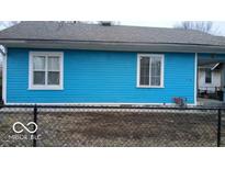 Charming exterior of this two-window home with a black chain fence and a bright blue facade at 3415 E 9Th St, Indianapolis, IN 46201