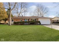 Charming ranch-style home featuring a brick exterior, a well-manicured lawn, and an attached two-car garage at 5201 Radnor Rd, Indianapolis, IN 46226