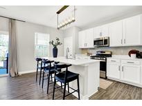 Modern kitchen featuring white cabinets, stainless steel appliances, a spacious island and hardwood flooring at 8148 Ebaugh Dr, Camby, IN 46113