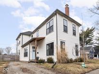 Charming two-story home featuring a brick chimney and a light blue front door at 910 Keystone Ave, Indianapolis, IN 46201