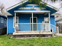Charming blue one-story home featuring a covered front porch, complemented by a small front yard at 945 N Ewing St, Indianapolis, IN 46201