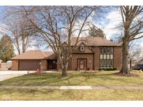 Charming brick home featuring a well-manicured lawn and a large mature tree in the front yard at 12107 Castle Row Overlook, Carmel, IN 46033