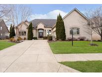 Stately cream brick home featuring manicured landscaping and a long driveway at 14020 Quarter Horse Ct, Carmel, IN 46032