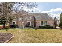Stunning brick home featuring a manicured lawn and mature trees on a sunny day at 7411 Perrier Dr, Indianapolis, IN 46278