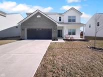 Two-story home with a gray brick garage and driveway, green grass, and a blue sky at 8310 Bearberry Ln, Pendleton, IN 46064