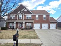 Charming two-story brick home with a three-car garage and a welcoming front porch at 13851 N Layton Mills Ct, Camby, IN 46113
