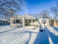 Winter backyard view featuring a quaint house, snow-covered lawn, and bare trees under a clear blue sky at 3920 S Sherman Dr, Indianapolis, IN 46237
