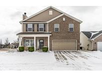 Charming two-story home featuring brick and vinyl siding, attached garage and manicured landscaping on a snow covered lawn at 6413 Green Grass Ln, Whitestown, IN 46075