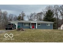Charming one-story home with a gray facade, a red door, mature trees, and a well-manicured lawn at 7165 N Kivett Rd, Monrovia, IN 46157