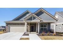 Charming gray home featuring stone accents, a two-car garage, and a welcoming front porch on a clear sunny day at 14116 Rowling Pl, Carmel, IN 46033