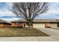 Charming brick home featuring a well-manicured lawn, mature tree, and attached two-car garage at 304 E 48Th St, Anderson, IN 46013