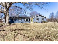 Charming blue single-story home with a sunny yellow front door and a well-manicured front yard at 320 E 86Th St, Indianapolis, IN 46240