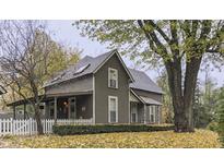 Charming two-story home with mature trees, covered porch, and white picket fence at 37 N Main St, Indianapolis, IN 46227