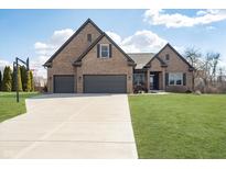 Stunning brick home featuring an attached three-car garage and a well manicured front yard at 6459 Canak Dr, Avon, IN 46123