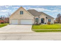 Beautiful brick home featuring a three-car garage, well-manicured lawn, and inviting entrance at 1434 Manchester Dr, Danville, IN 46122