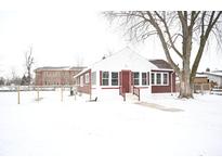 Quaint single-story brick home featuring well-maintained landscaping and a cozy front porch in a winter setting at 1460 Waldemere Ave, Indianapolis, IN 46241