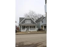 Attractive gray home featuring a covered porch with decorative columns and a well-maintained lawn at 21 S Warman Ave, Indianapolis, IN 46222