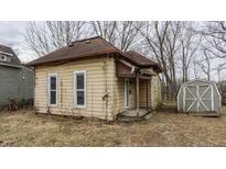 Side view of a run-down, one-story home featuring a small porch and an unkempt yard with a shed at 271 S 5Th St, Noblesville, IN 46060