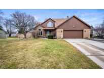 Charming brick home featuring a two-car garage and well-maintained lawn with mature trees at 7703 Geist Estates Ct, Indianapolis, IN 46236