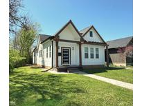 Charming exterior showcasing a well-maintained lawn and inviting facade with light colored siding and dark trim at 1818 N Cornell Ave, Indianapolis, IN 46202
