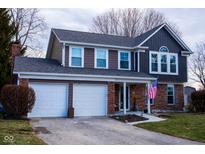 Charming two-story home with a two car garage, neutral brown siding, an American flag, and a well-manicured lawn at 959 Vicksburg N Dr, Greenwood, IN 46143