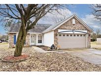 Charming brick home featuring a two-car garage, well-manicured lawn, and mature tree in the front yard at 2027 Ferdinand Ct, Indianapolis, IN 46234
