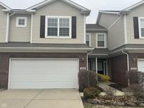 Two-story townhome featuring a brick base and tan siding, with an attached two-car garage at 4088 Weston Pointe Dr, Zionsville, IN 46077