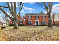 Charming two-story red brick home with blue shutters surrounded by mature trees and a green front lawn at 4783 Briarwood Trce, Carmel, IN 46033