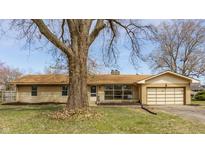 Charming single-story home with a tan brick exterior, attached garage, and mature landscaping at 5210 Ashbourne Ln, Indianapolis, IN 46226