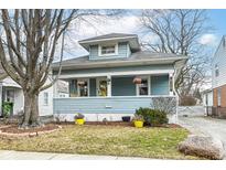 Charming blue two-story home with a welcoming front porch and vibrant yellow accents at 6179 Norwaldo Ave, Indianapolis, IN 46220